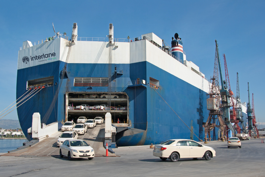 Vehicles being loaded onto a large Interlane cargo ship at a port, illustrating international car shipping operations.