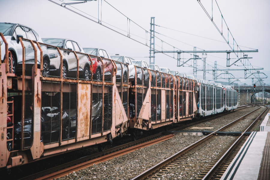 Vehicles loaded on a railcar at a train station for long-distance car shipping.
