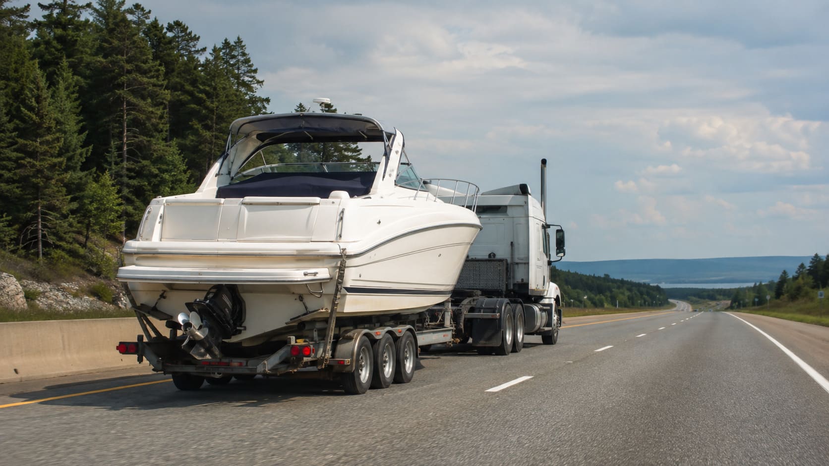 Recreational boat on a trailer being transported by truck on a Canadian highway